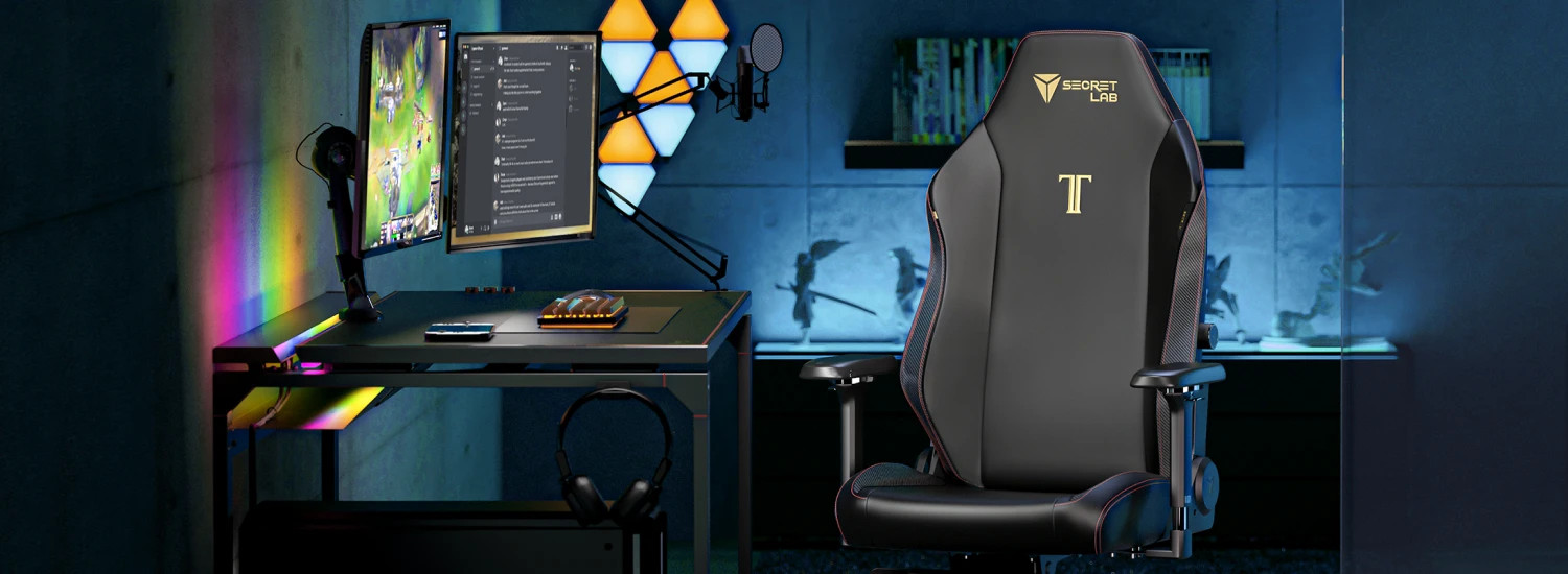 A sleek gaming setup features a black gaming chair with logo, a desk with a dual-monitor setup displaying a game and chat, a microphone, and ambient RGB lighting. Decorative shelves hold action figures against a dimly lit blue wall.
